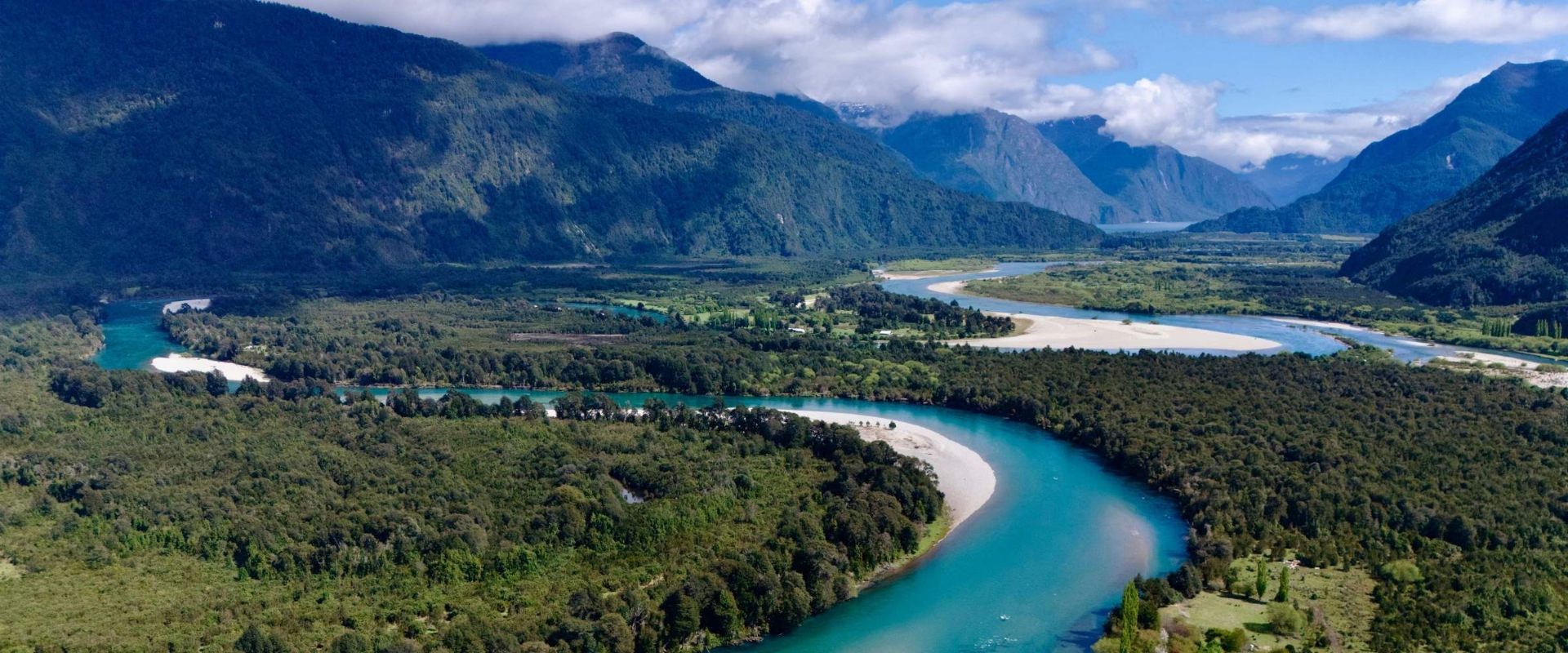 Vista aérea de un valle de la Patagonia chilena con un río turquesa serpenteando entre bosques y montañas