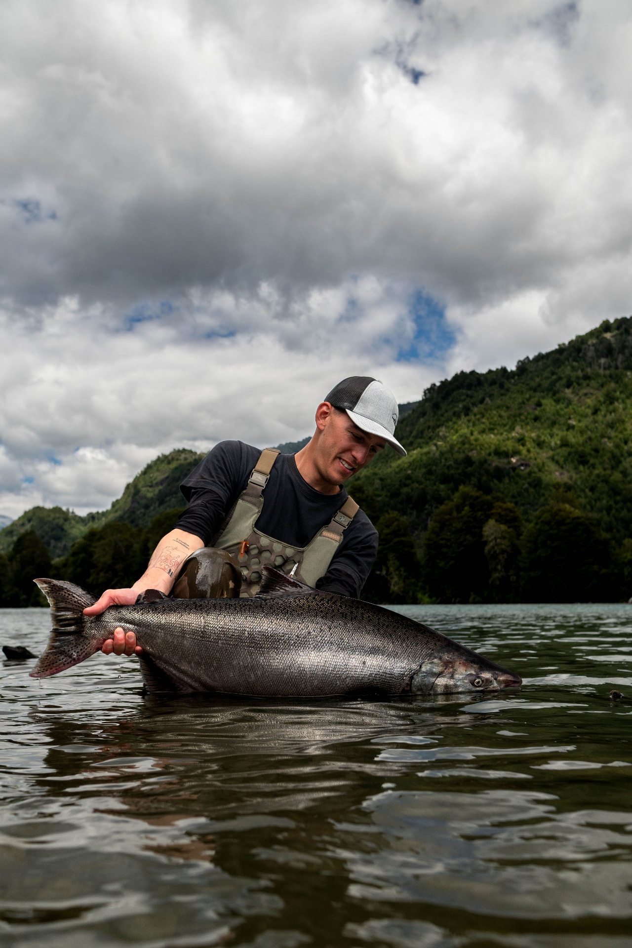 Retrato de Luciano Tortarolo sosteniendo un salmón en un río de la Patagonia chilena
